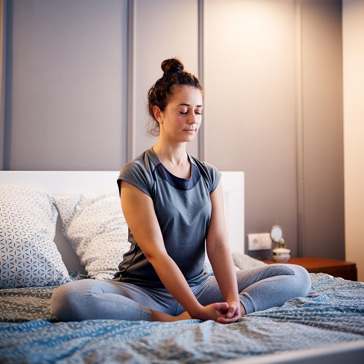 Woman practicing meditation as part of relaxing bedtime routine for better sleep